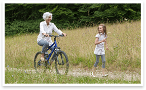 A female child running ahead of her lady companion riding a bike