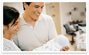 A smiling couple holding a newborn baby