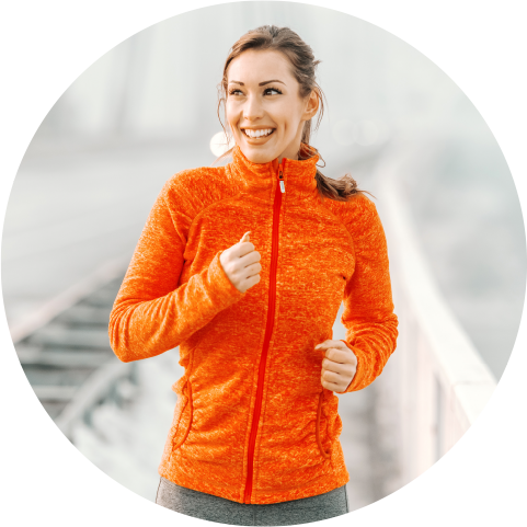 Smiling young woman jogging in orange jacket
