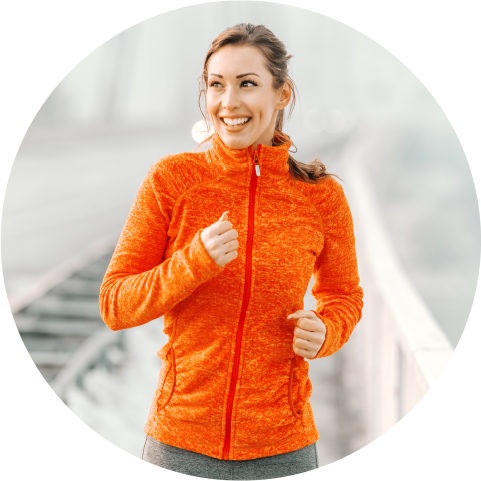 GettyImages-1095331560 Smiling young woman jogging in orange jacket