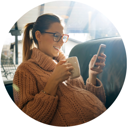 iron-d-image8 Pregnant woman with glasses smiling at phone, holding cup of coffee in other hand